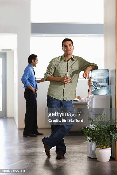 businessman standing by water cooler in office - leaning stock pictures, royalty-free photos & images