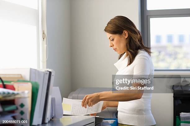 young businesswoman sorting through paperwork in office - akten ablegen stock-fotos und bilder