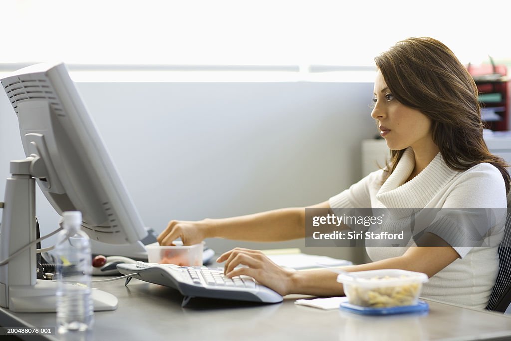 Young businesswoman eating lunch at desk