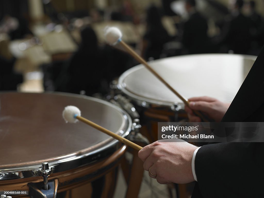 Male timpanist playing kettledrums in orchestra, close-up