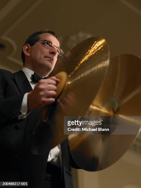 male percussionist playing cymbals in orchestra, low angle view - orchester stock-fotos und bilder