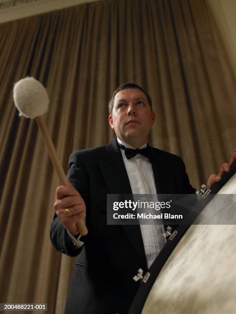 male percussionist playing bass drum in orchestra, low angle view - bass drum stock pictures, royalty-free photos & images