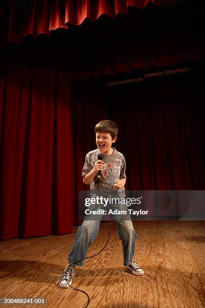 boy (8-10) performing on stage, singing into microphone - boy singing stock-fotos und bilder