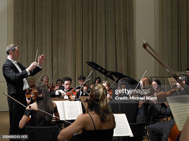 conductor leading orchestra - symphony stockfoto's en -beelden