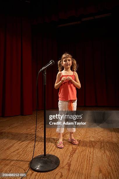 girl (5-7) standing on stage, looking at microphone stand - microfoonstandaard stockfoto's en -beelden