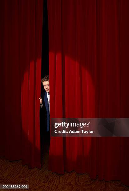 spotlight on on boy (11-13) looking through curtains on stage - behind the curtain stock pictures, royalty-free photos & images