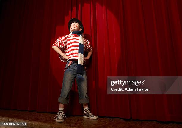 spotlight on boy (8-10) in clown outfit, hands on hips, low angle view - clown hat stock pictures, royalty-free photos & images