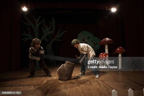 two boys (9-11) acting as lumberjacks on stage, sawing tree stump - school play stock pictures, royalty-free photos & images