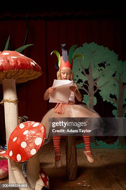 girl (4-6) on stage, sitting on giant toadstool practicing lines - skolpjäs bildbanksfoton och bilder