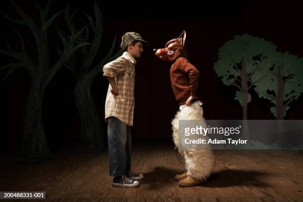 two boys (9-11) acting on stage, one boy confronting other as bad wolf - attore foto e immagini stock