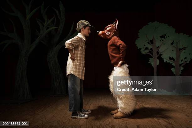 two boys (9-11) acting on stage, one boy confronting other as bad wolf - acteren stockfoto's en -beelden