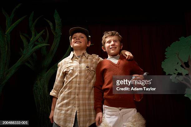 two boys (9-11) with arms around each other on stage, smiling - acting performance stock pictures, royalty-free photos & images