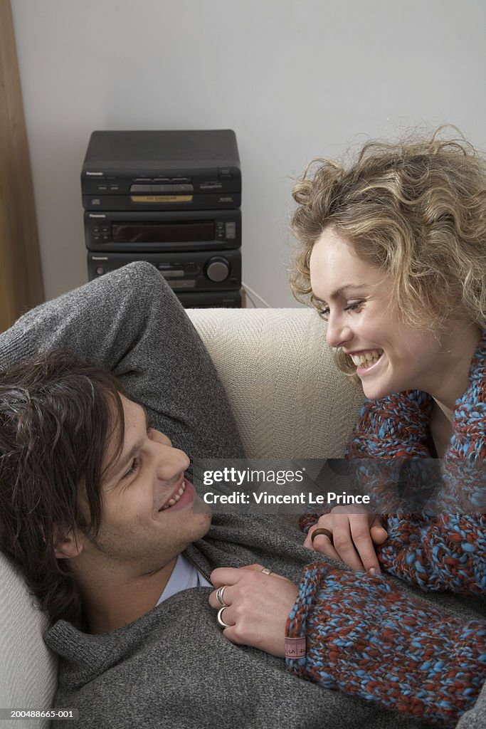 Couple embracing on sofa, laughing, close-up, side view