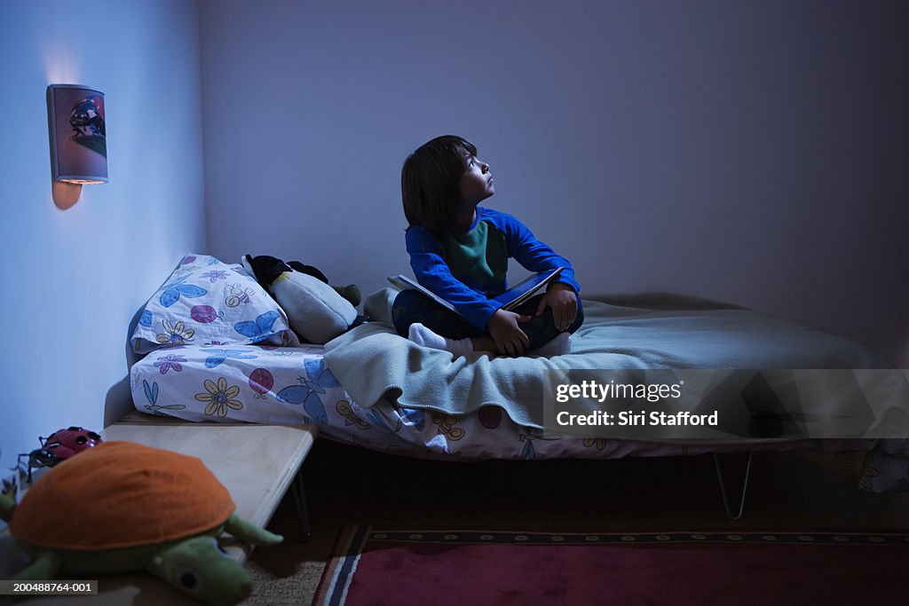 Boy (8-10) sitting in bed, looking up