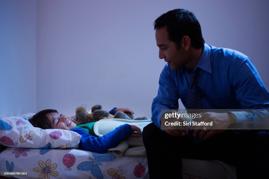 Father tucking son (8-10) in bed