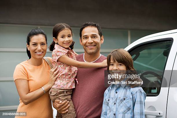 family standing outside house next to car - vier personen stockfoto's en -beelden