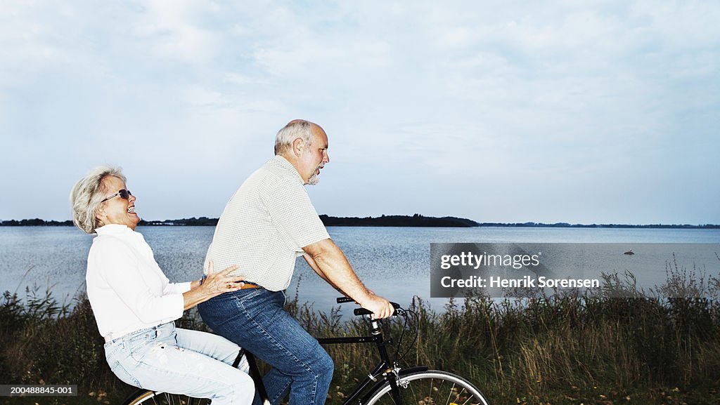 Mature couple riding bicycle, side view