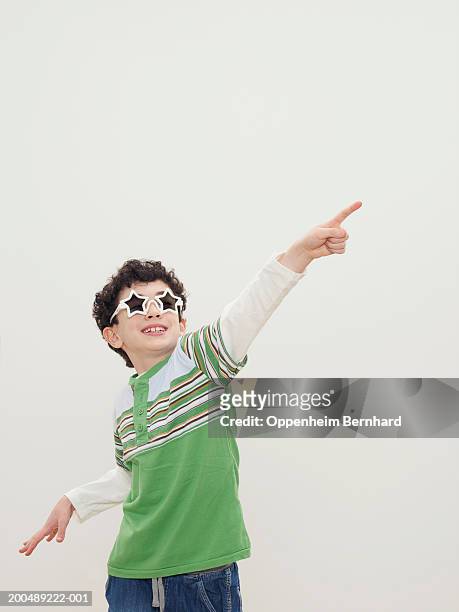 boy (7-9) wearing star-shaped sunglasses, pointing - 6 point star stockfoto's en -beelden
