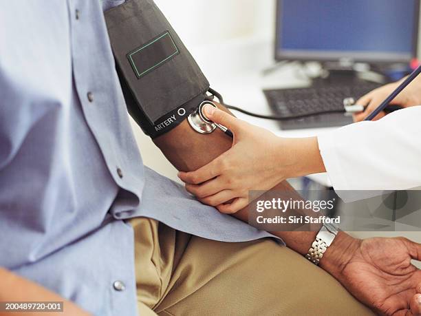 female doctor taking patient's blood pressure - stethoskop stock-fotos und bilder