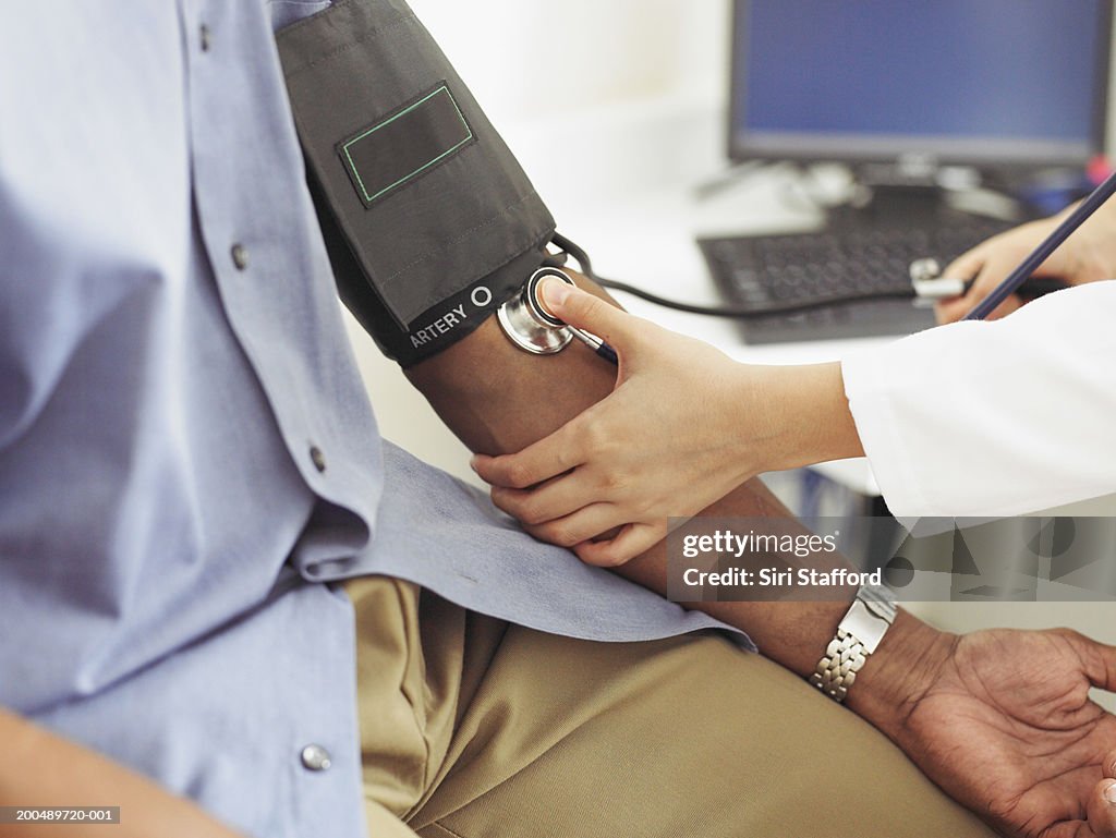 Female doctor taking patient's blood pressure
