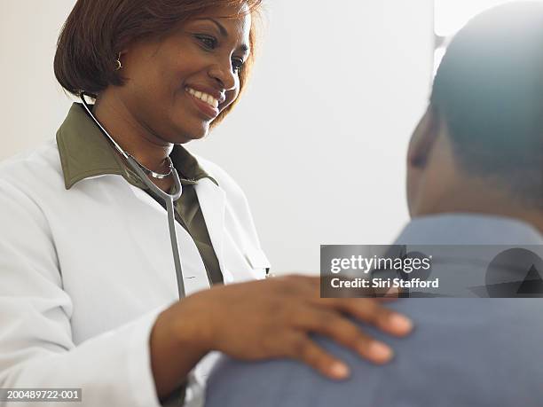 female doctor talking to patient - man touching shoulder stock-fotos und bilder