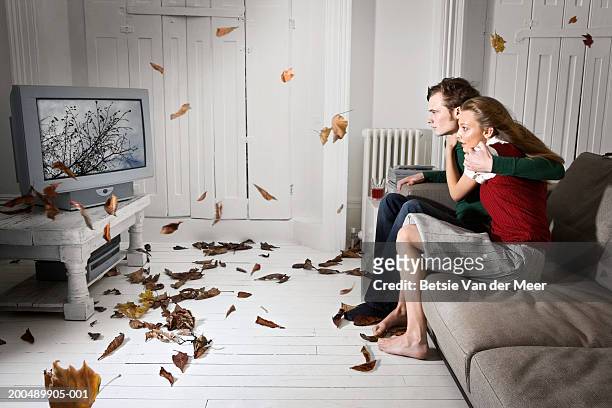 couple watching television as storm blows from screen into living room - home cinema stockfoto's en -beelden