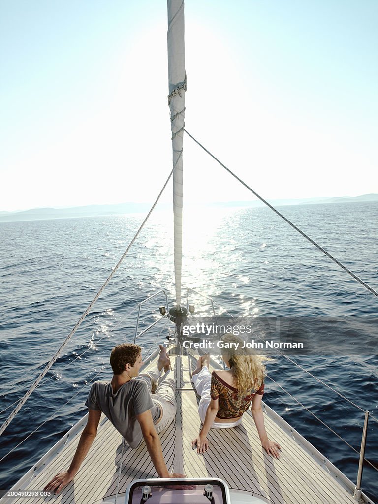 Couple sitting on deck of yacht, rear view