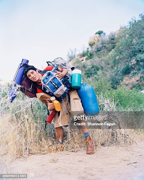 young man carrying backpack and camping gear outdoors - over burdened stock pictures, royalty-free photos & images