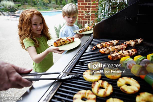 children (5-8) getting helpings of food from barbecue grill - kebab stock pictures, royalty-free photos & images