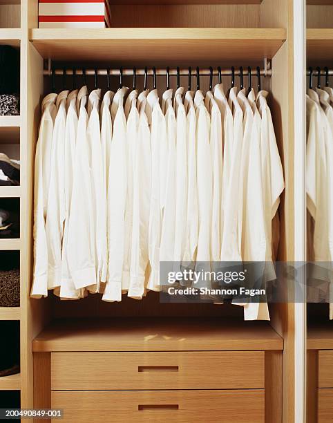 white shirts hanging in closet - camisa blanca fotografías e imágenes de stock