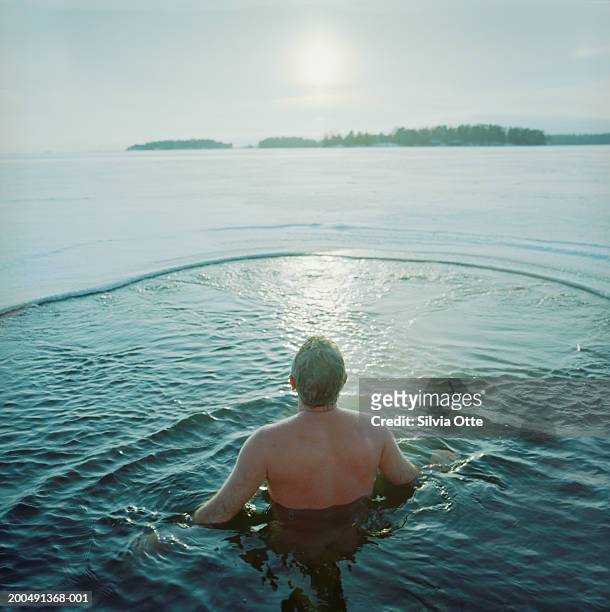 finland, helsinki, man ice water swimming in frozen baltic sea - finnland stock-fotos und bilder
