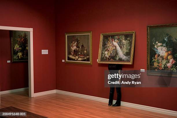 woman standing behind painting on wall in art gallery - hiding stockfoto's en -beelden