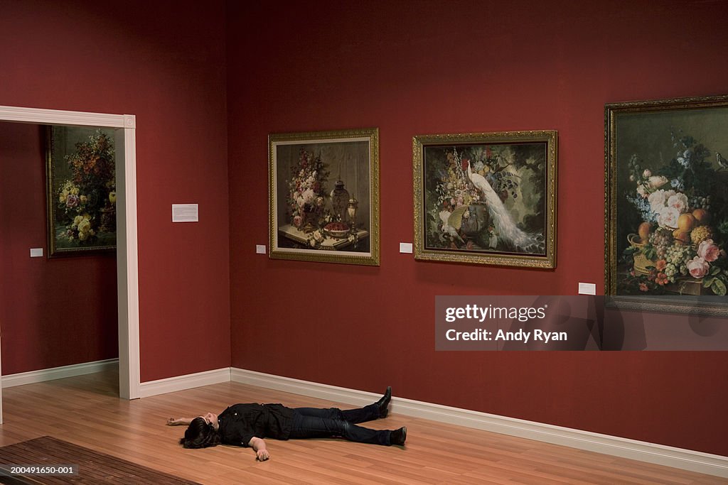 Woman lying unconscious on art gallery floor