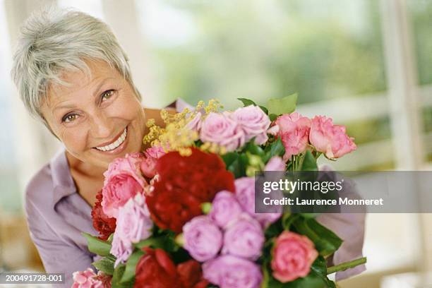 senior woman holding bouquet of flowers, smiling, close-up, portrait - close up of flower bouquet stock-fotos und bilder