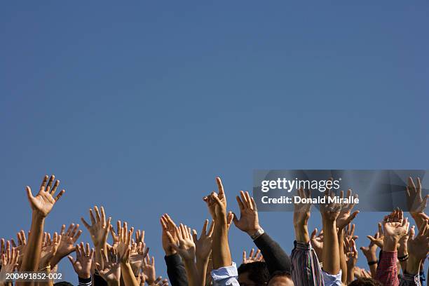 crowd raising hands in air - waving hand stock-fotos und bilder