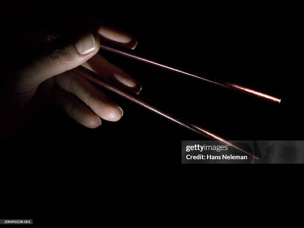 Woman holding chopsticks spread apart, close-up