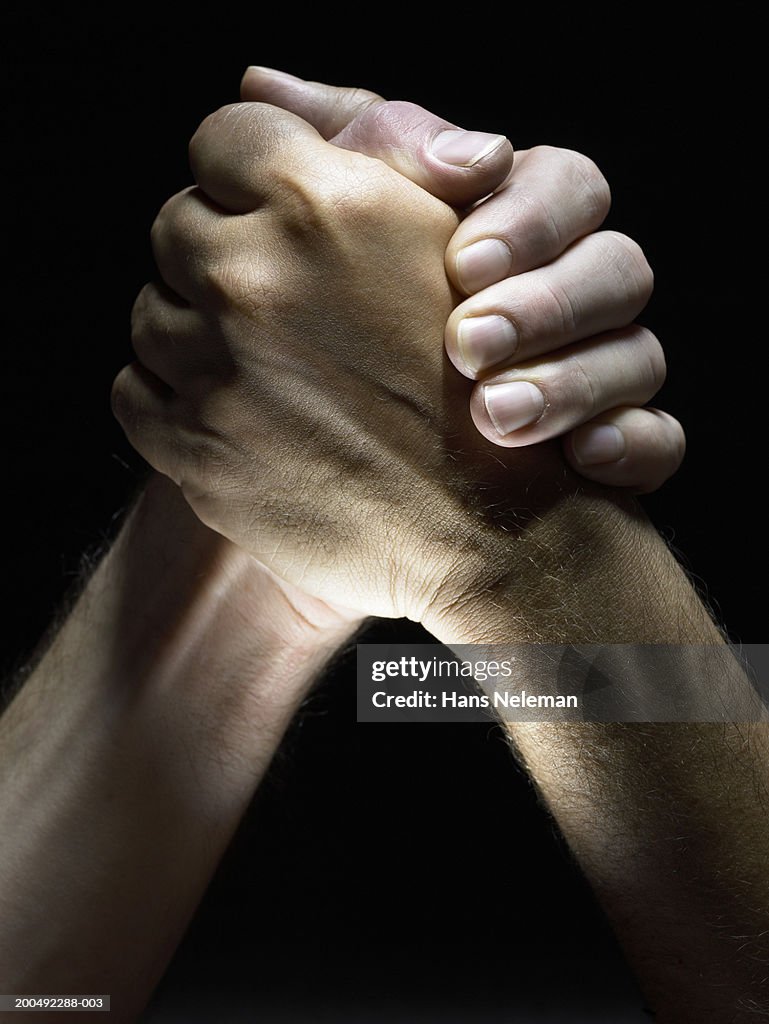 Two men clasping hands, close-up, side view