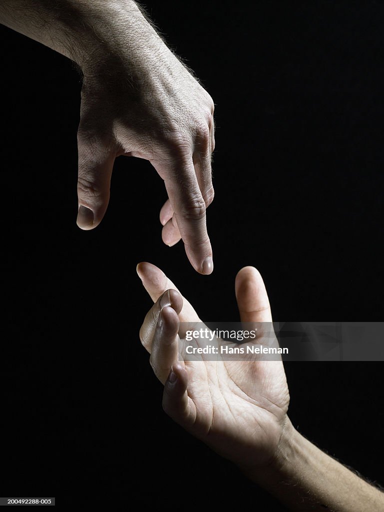 Two male hands reaching towards each other, close-up, side view