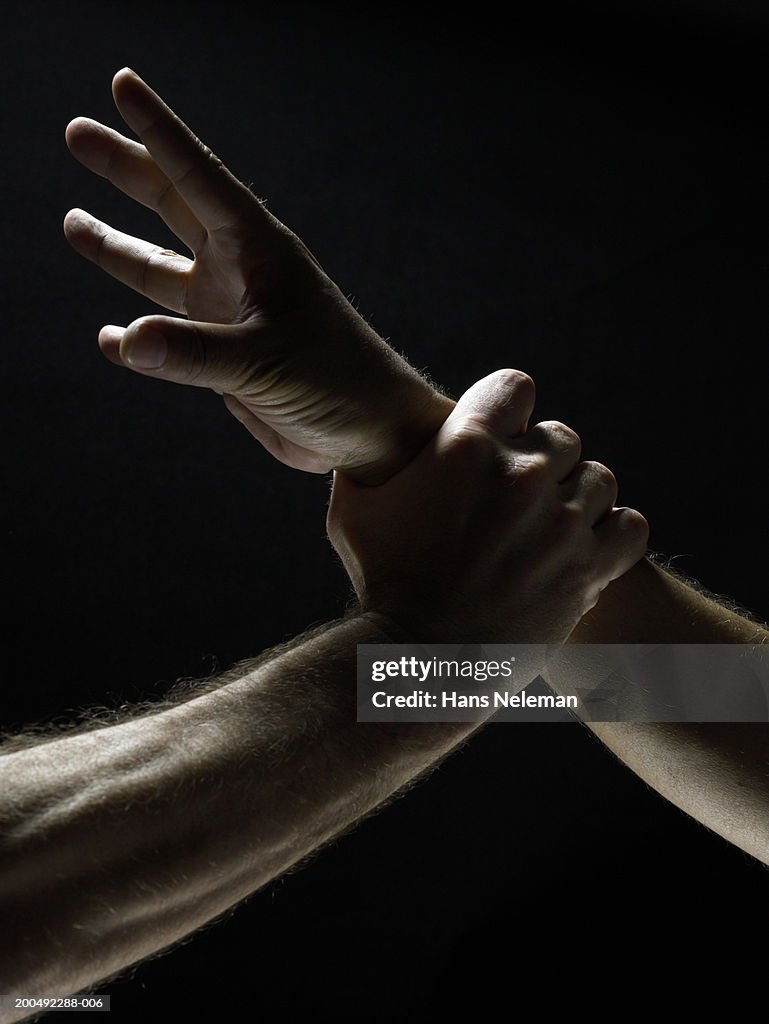 Man grabbing another man by his wrist, close-up, side view