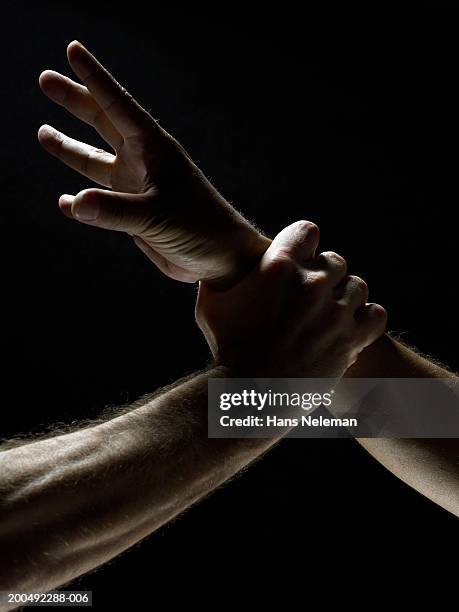 man grabbing another man by his wrist, close-up, side view - restraining photos et images de collection