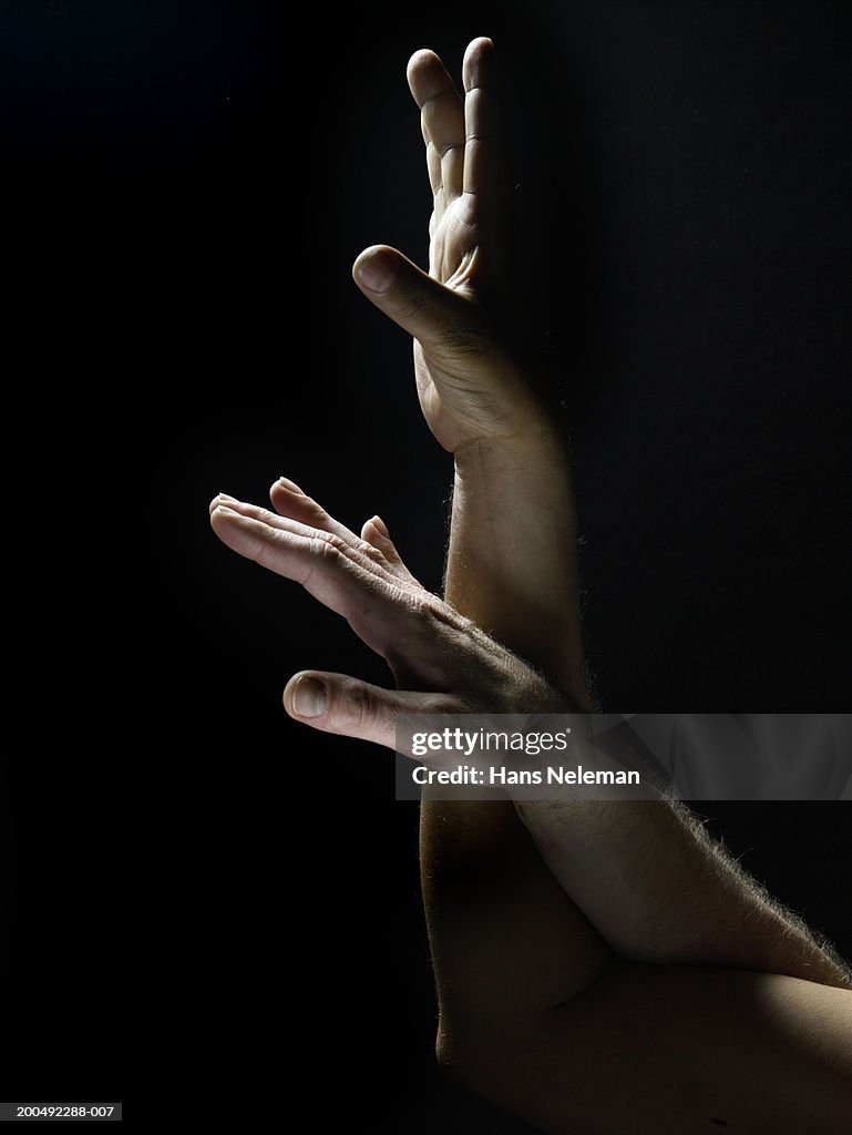 Two male hands reaching upwards, arms intertwined, close-up, side view