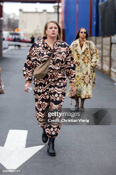 Guest wears overall with print, brown bag, black ankle boots outside Ulla Johnson on February 11, 2024 in New York City.