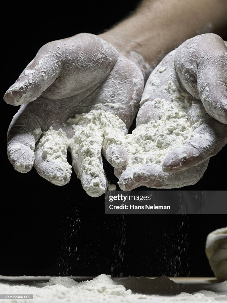 Person holding flour in palm of hands, close-up