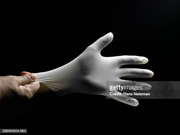 person putting on white surgical glove, close-up of hand, side view - surgical glove stock pictures, royalty-free photos & images