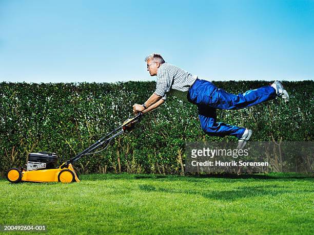 senior man mowing lawn, jumping, side view - bush live stock-fotos und bilder