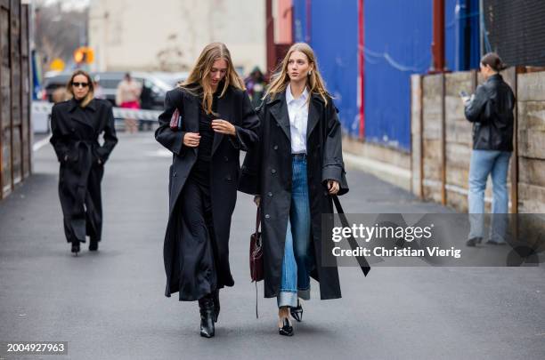 Twins Amalie & Cecilie Moosgaard wearing black trench coat, denim jeans, white button shirt outside Ulla Johnson on February 11, 2024 in New York...