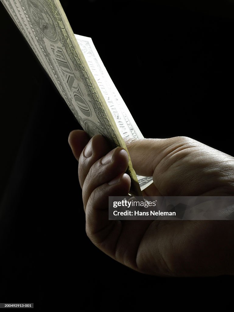 Man holding dollar bills, close-up, side view