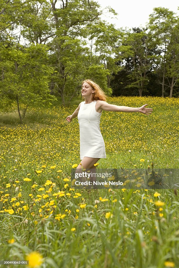 Young woman in field, arms outstretched