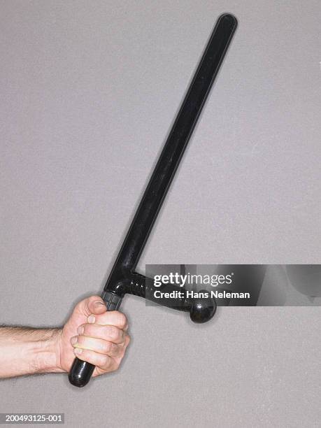 man holding police baton, side view - truncheon stockfoto's en -beelden