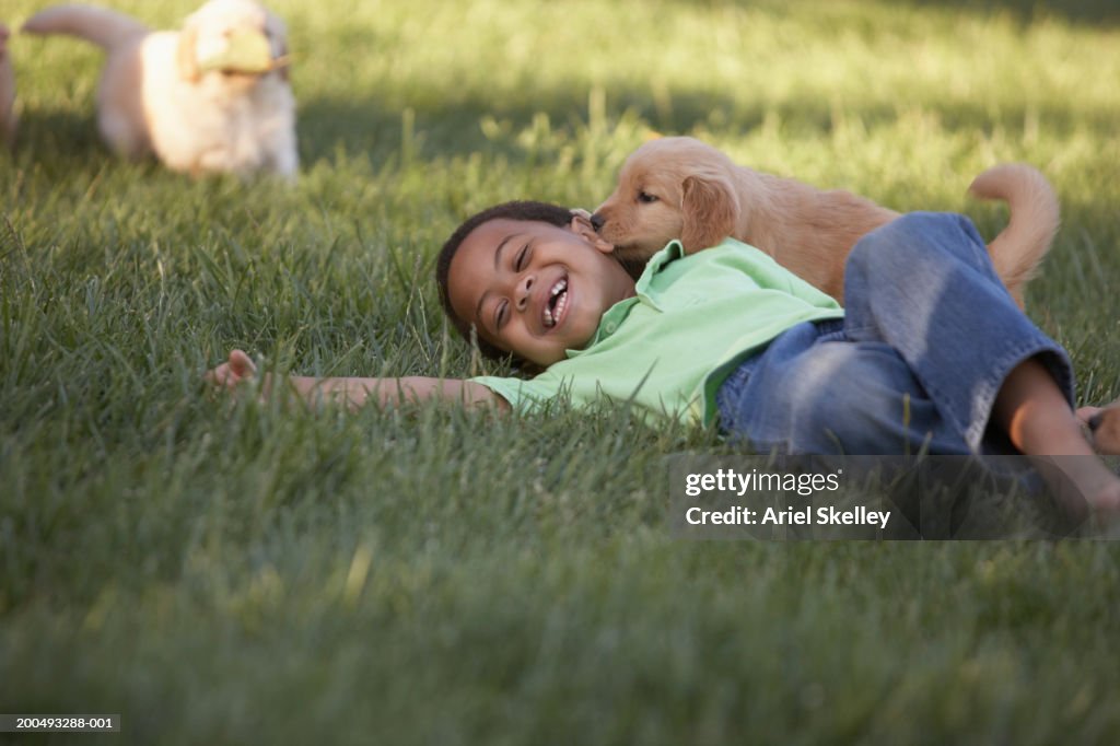 Boy (5-7) on grass with dog, smiling